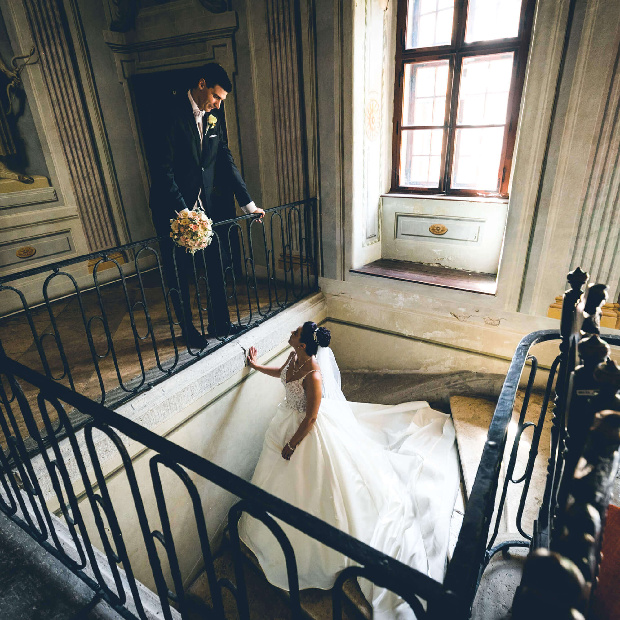 Esküvő fotózás során készült esküvői fotó. Judit áll a lépcsőn és Tamásra néz.