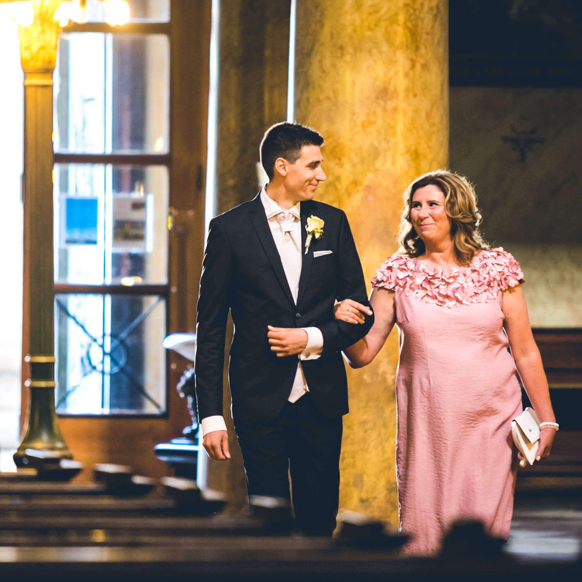 Esküvő fotózás során készített kép Tamásról és anyukájáról amikor sétálnak a templomban.