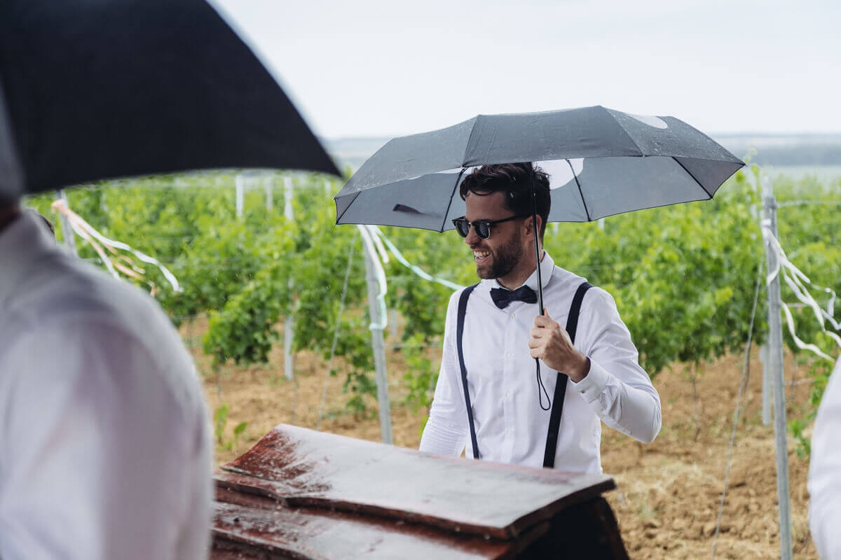 Esküvő fotózás során készült kép egy vendégről, aki az esőben áll.