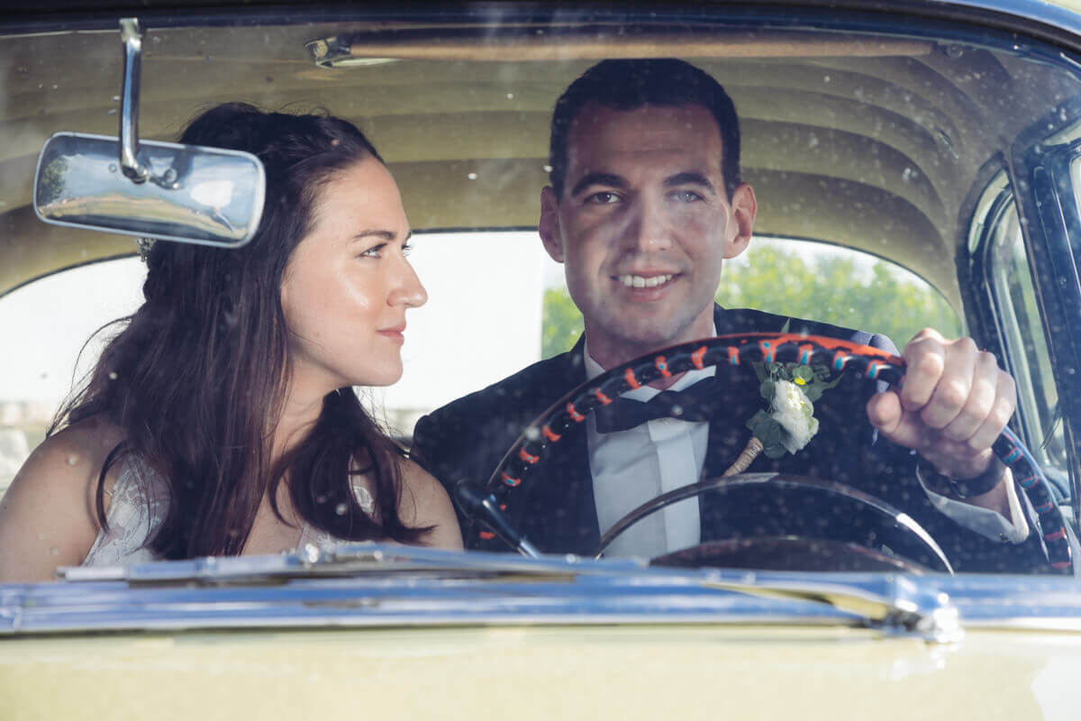 Esküvő fotózás során készült kép. Nóri és Zoli ül egy autóban.
